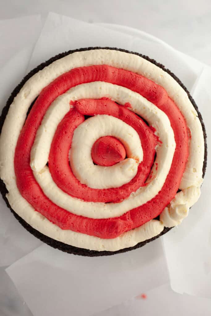 A chocolate cake, frosted with red and white frosting in a bullseye pattern.