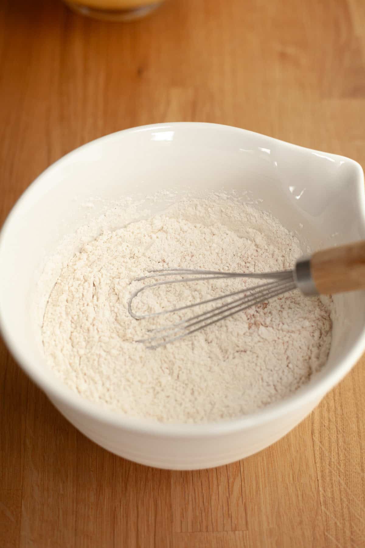 A white bowl with flour and a whisk.