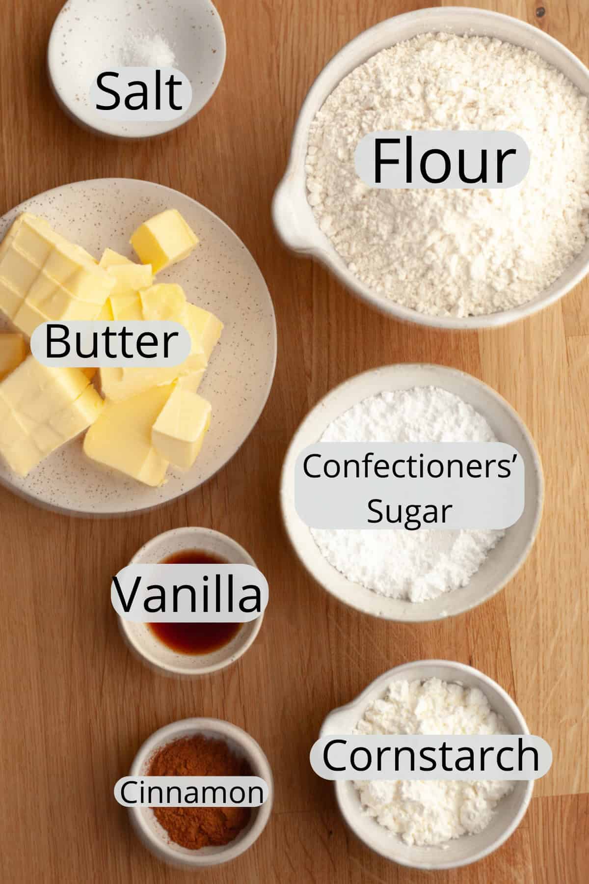 All the ingredients needed to make cinnamon shortbread cookies, weighed out into small bowls.