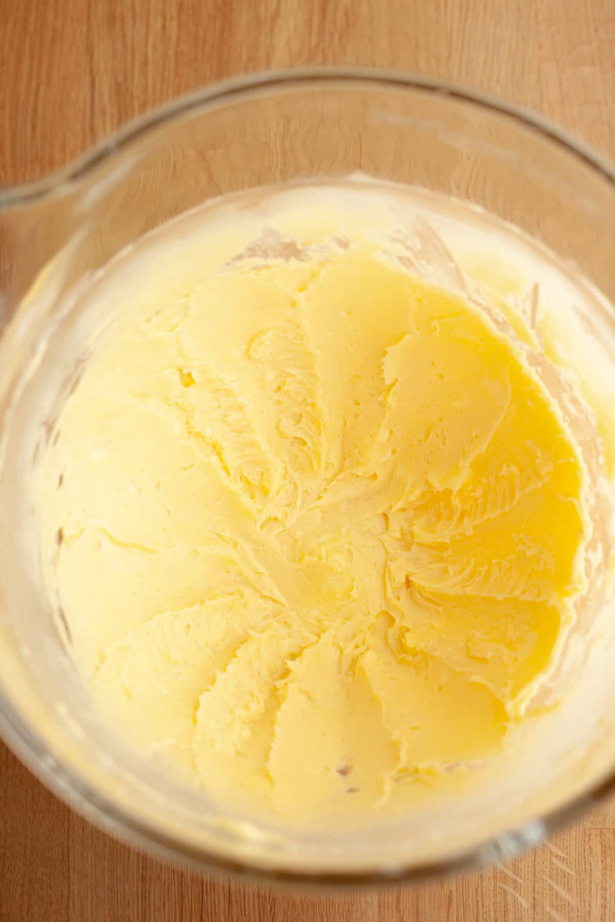 A large glass bowl with creamed butter and sugar.