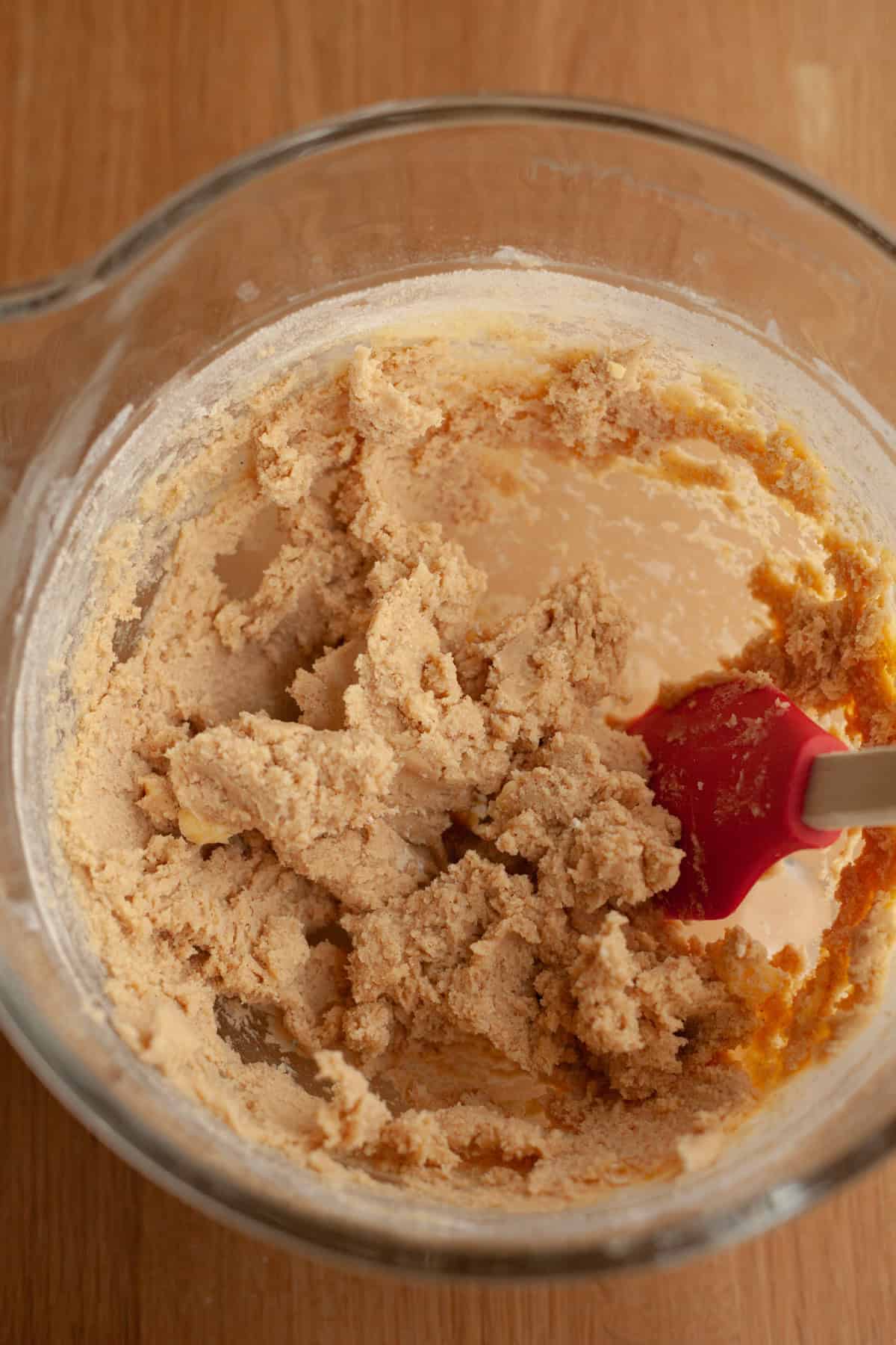 A large glass mixing bowl with cookie dough.