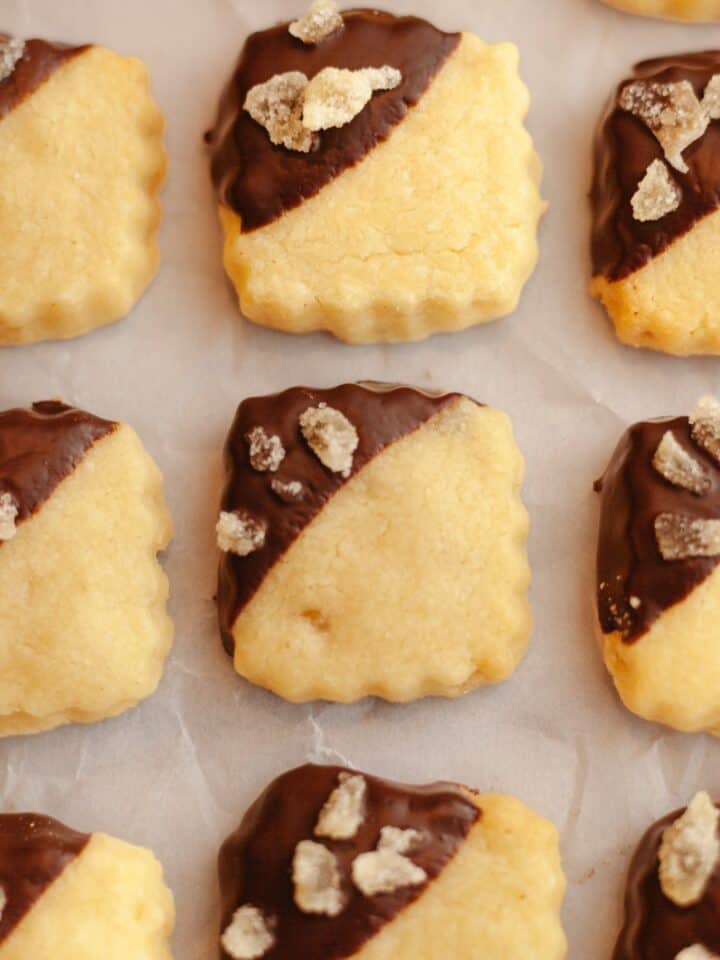 Three lines of ginger shortbread cookies, half dipped in chocolate and crystallized ginger.
