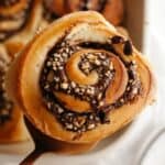 A close up of a Nutella cinnamon roll with chopped hazelnuts.
