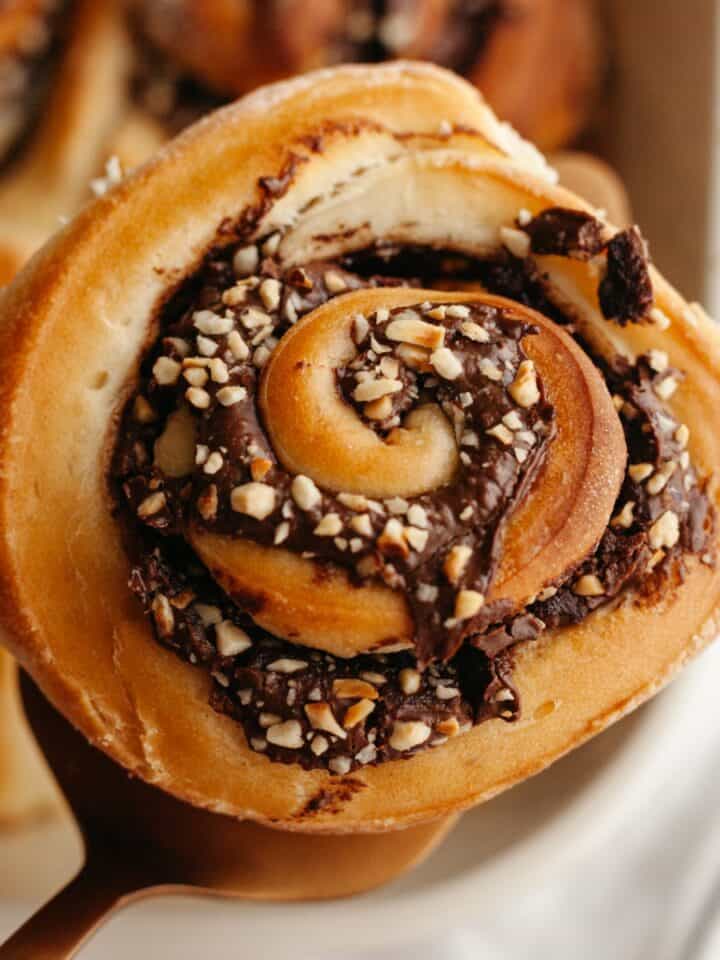 A close up of a Nutella cinnamon roll with chopped hazelnuts.