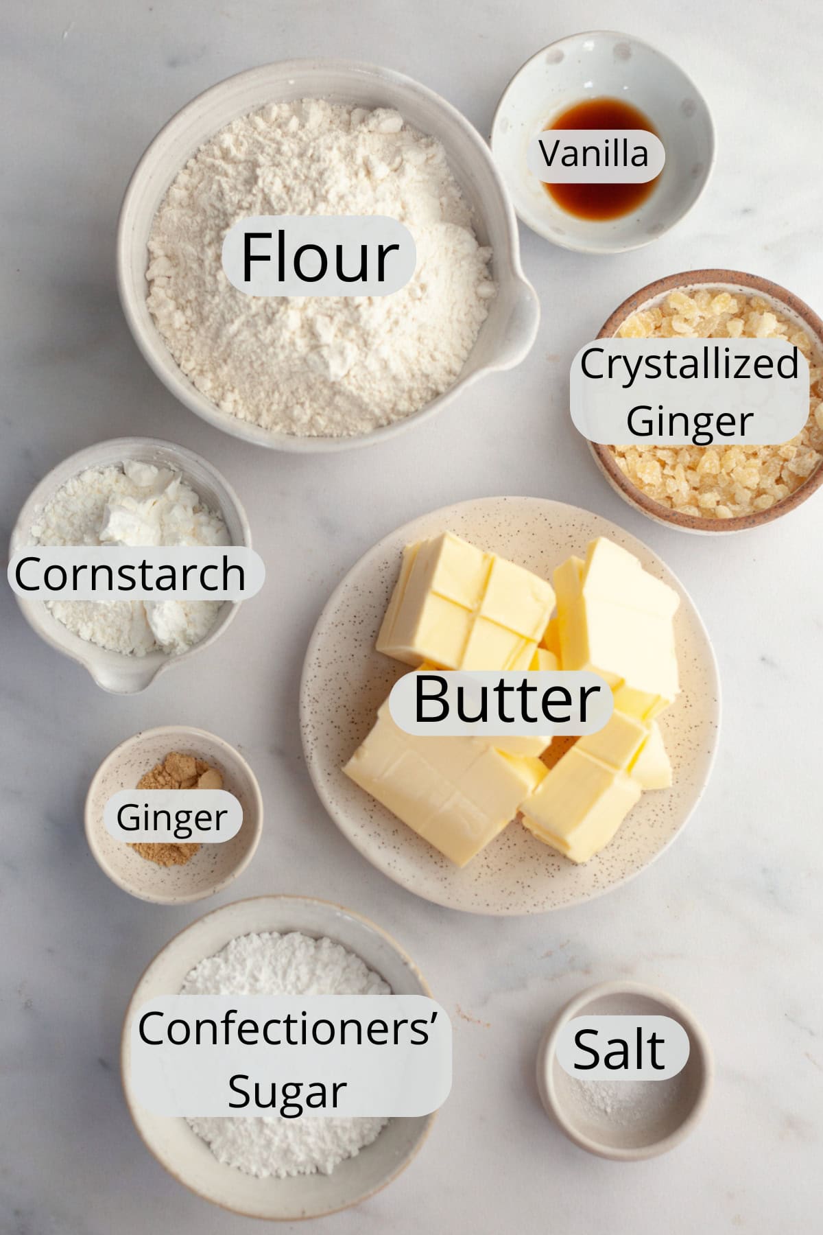 All the ingredients needed to make ginger shortbread cookies, weighed out into small bowls.