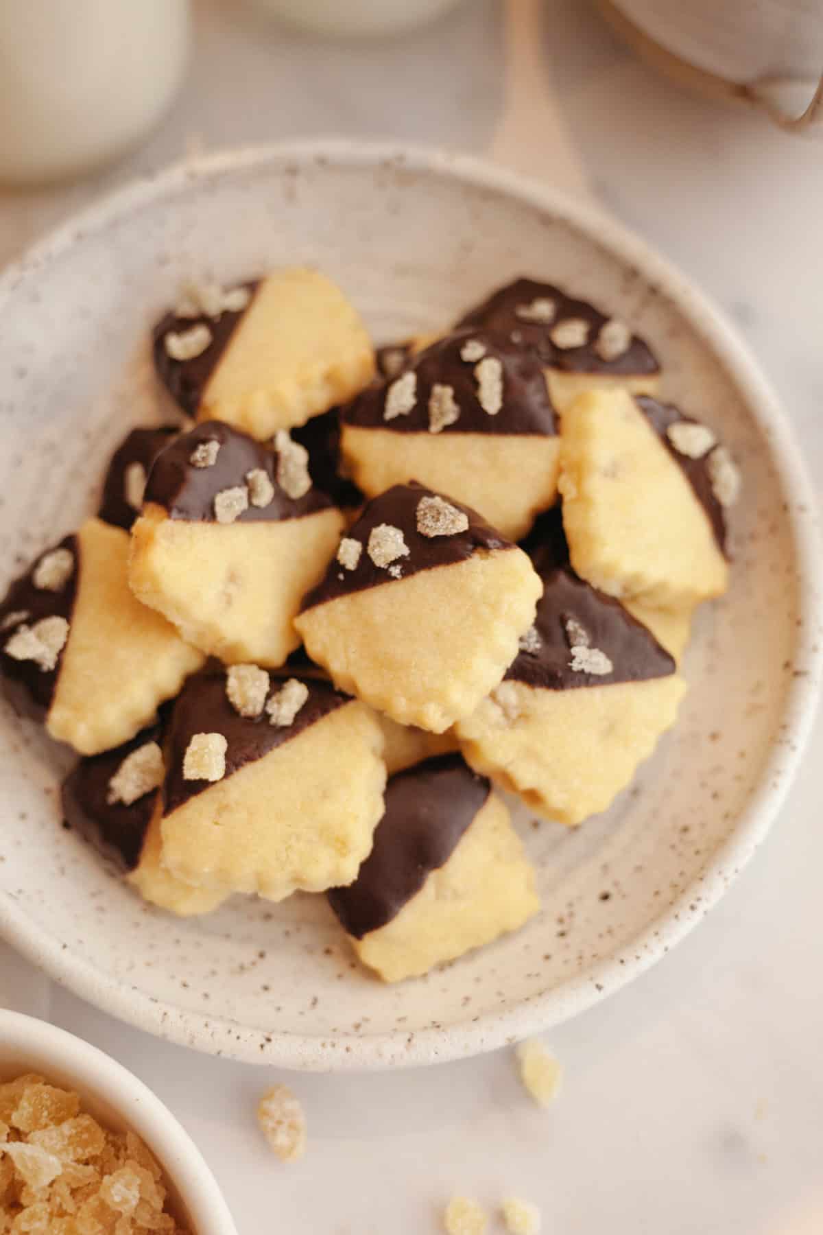 A plate full of small ginger shortbread cookies, half dipped in chocolate.