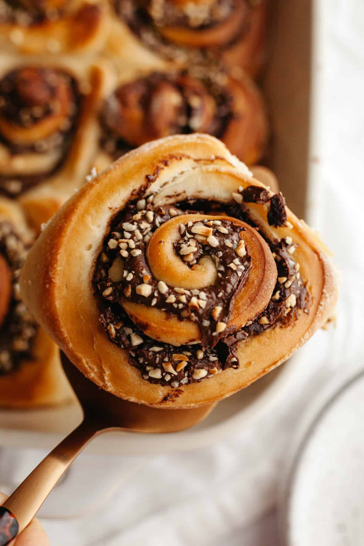 A close up of a Nutella cinnamon roll with chopped hazelnuts.