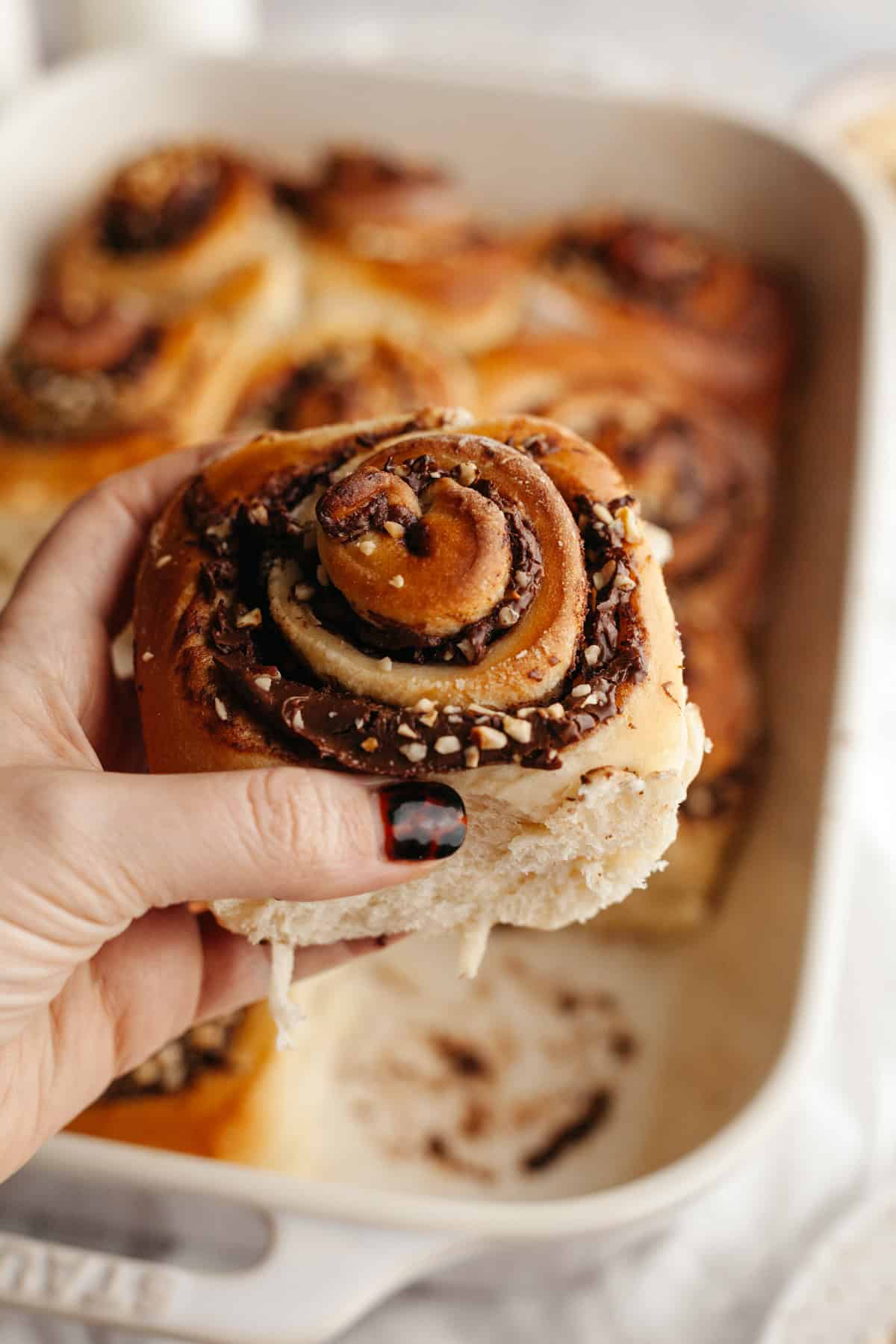 A close up of a Nutella cinnamon roll with chopped hazelnuts.