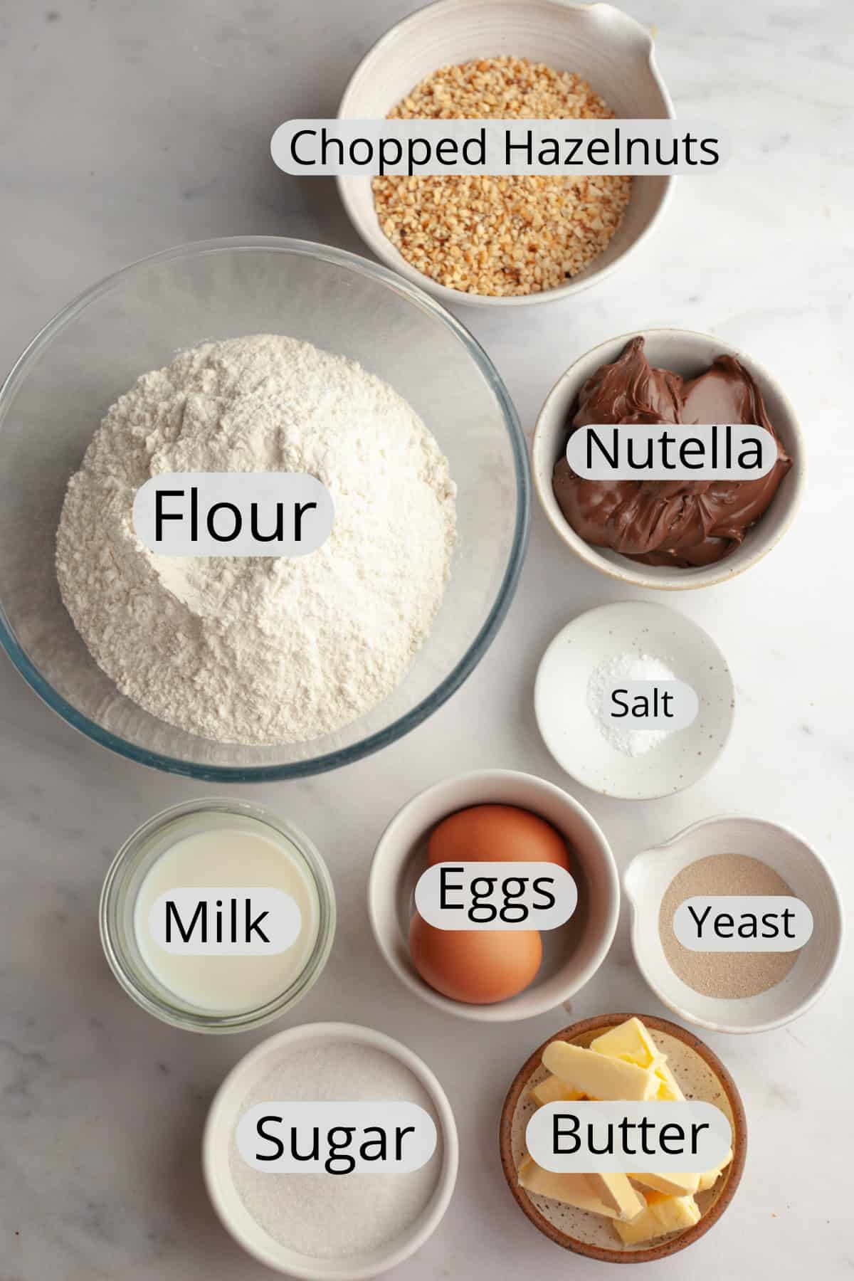 All the ingredients needed to make Nutella cinnamon rolls, weighed out into small bowls.