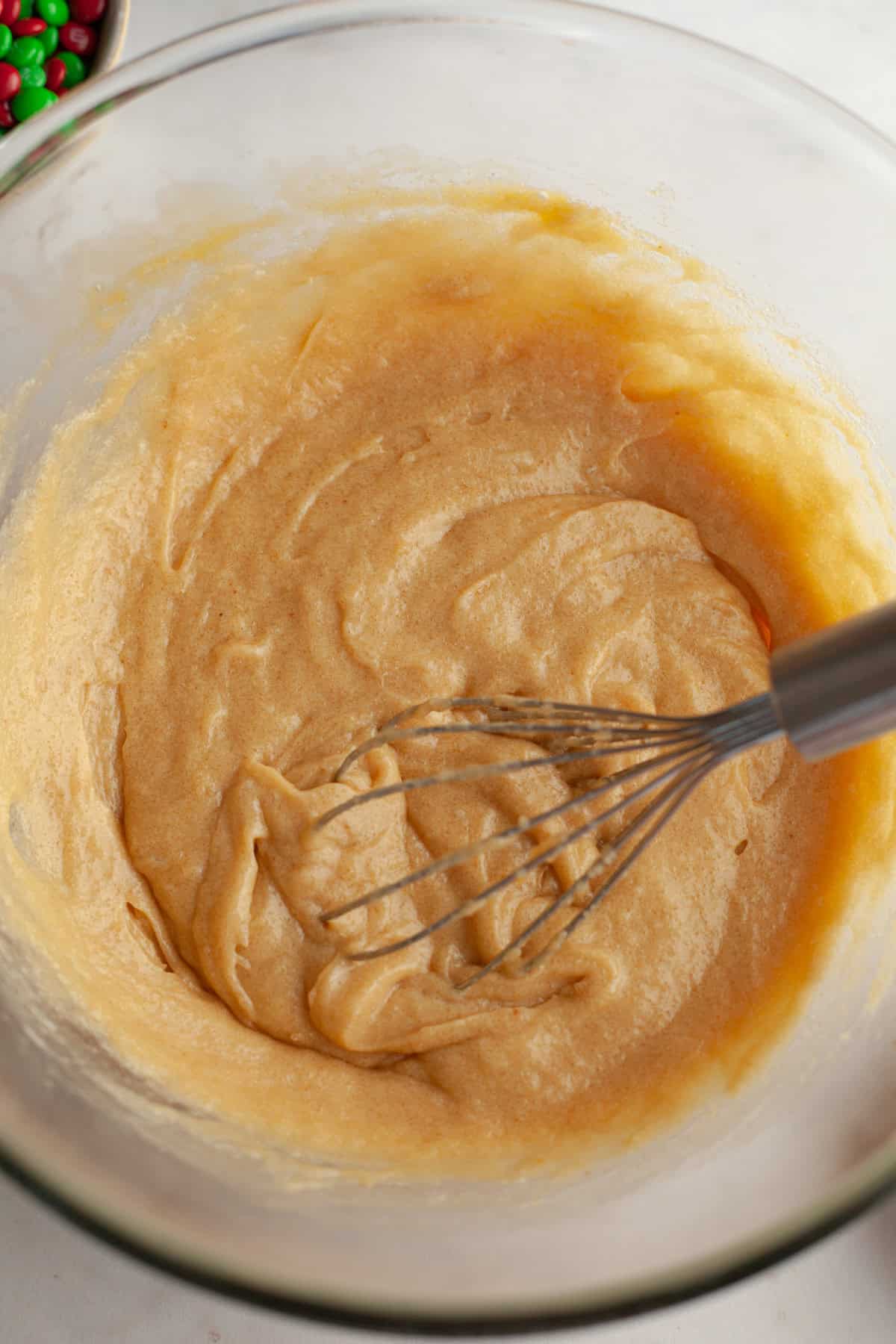 oatmeal cookie dough in a glass bowl with a whisk.
