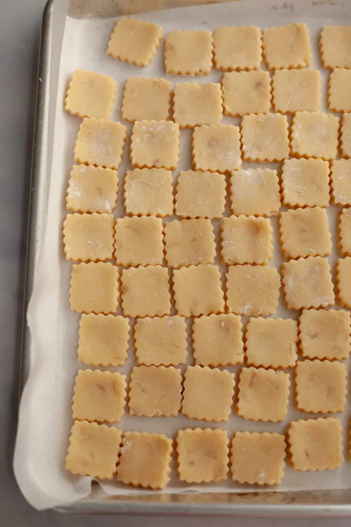 Unbaked ginger cookies on a parchment lined baking sheet.