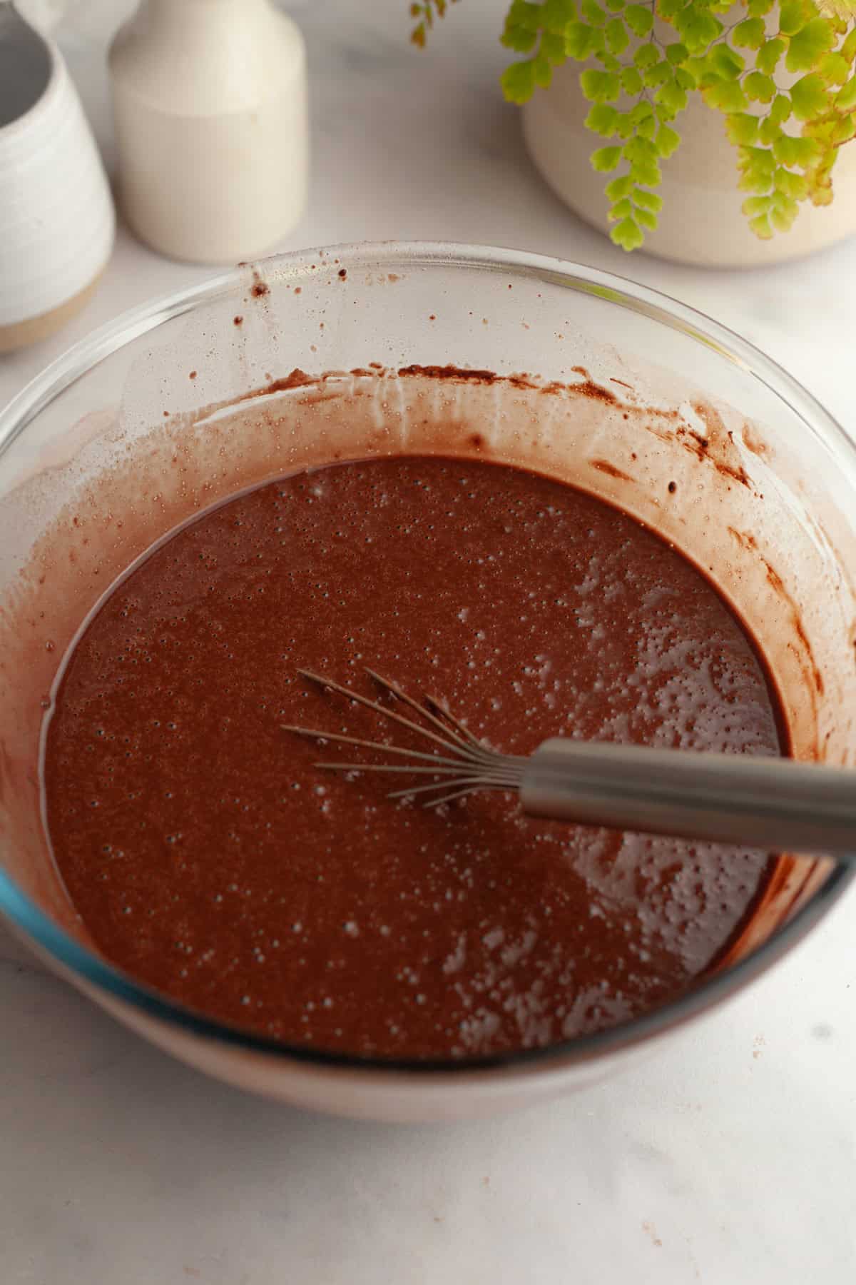 Chocolate cake batter in a glass bowl.