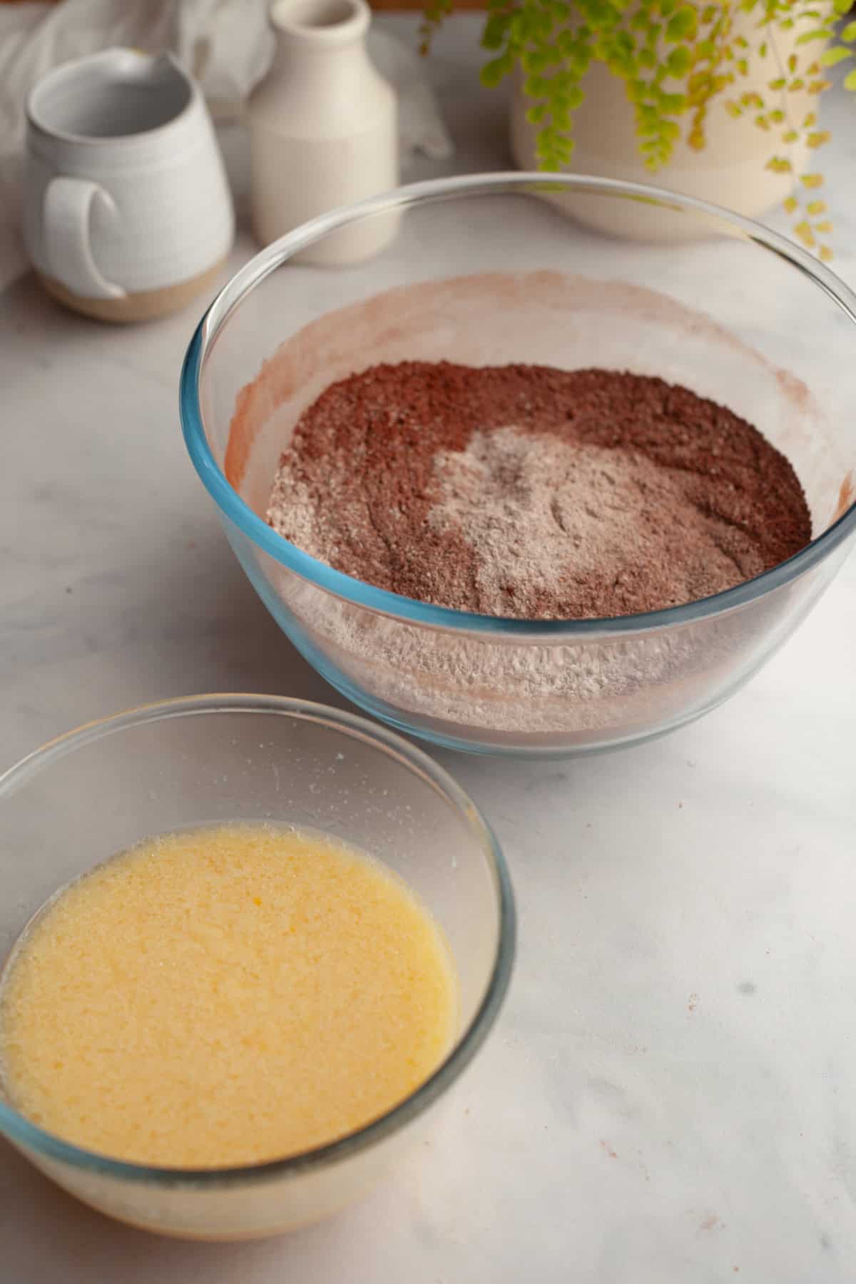 A bowl with flour and cocoa powder and a smaller bowl with whisked eggs in it.