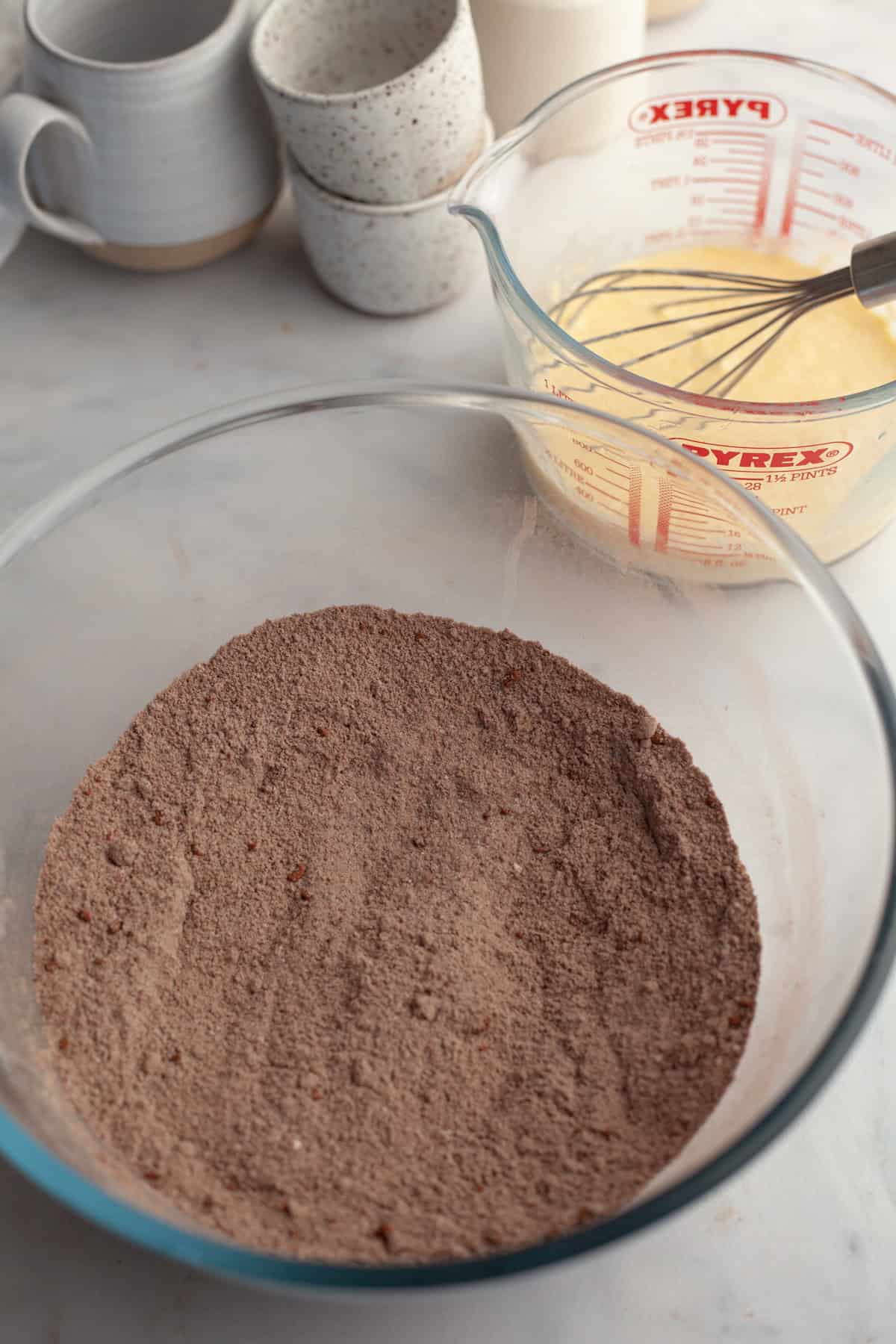 A glass bowl with flour and cocoa powder.