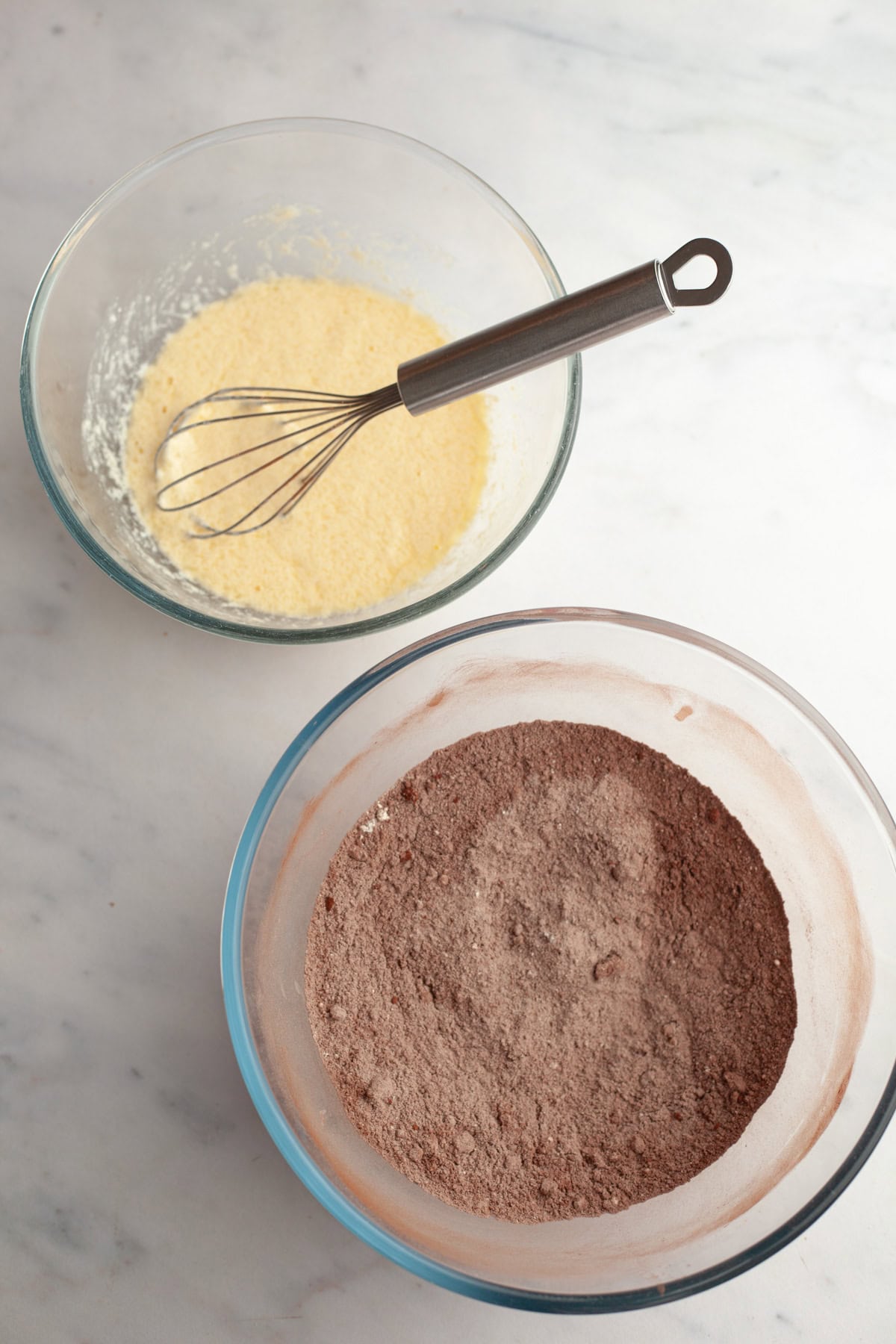 A small bowl with whisked eggs and buttermilk, and a large bowl with flour and cocoa powder.