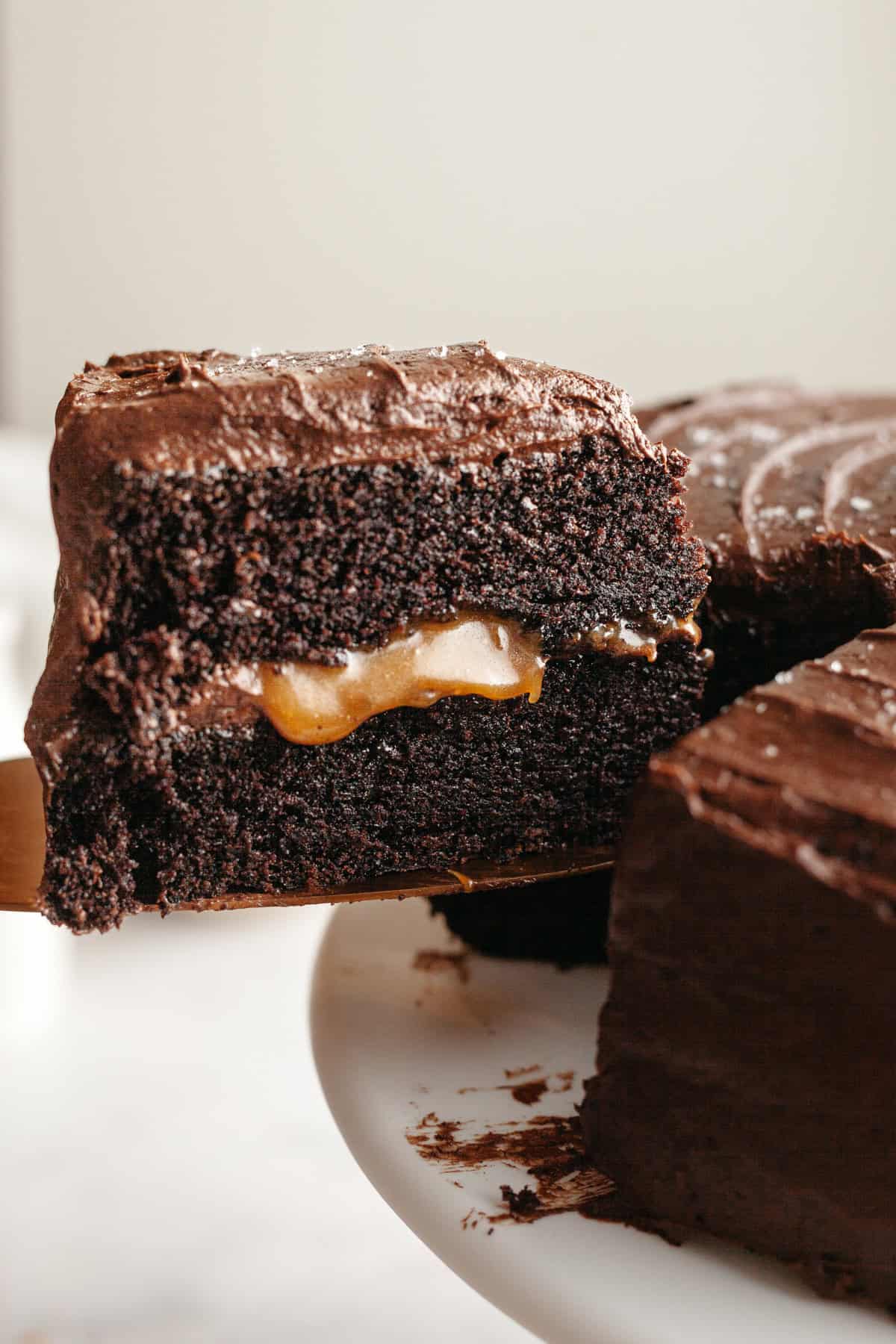 A slice of caramel chocolate cake being lifted out.