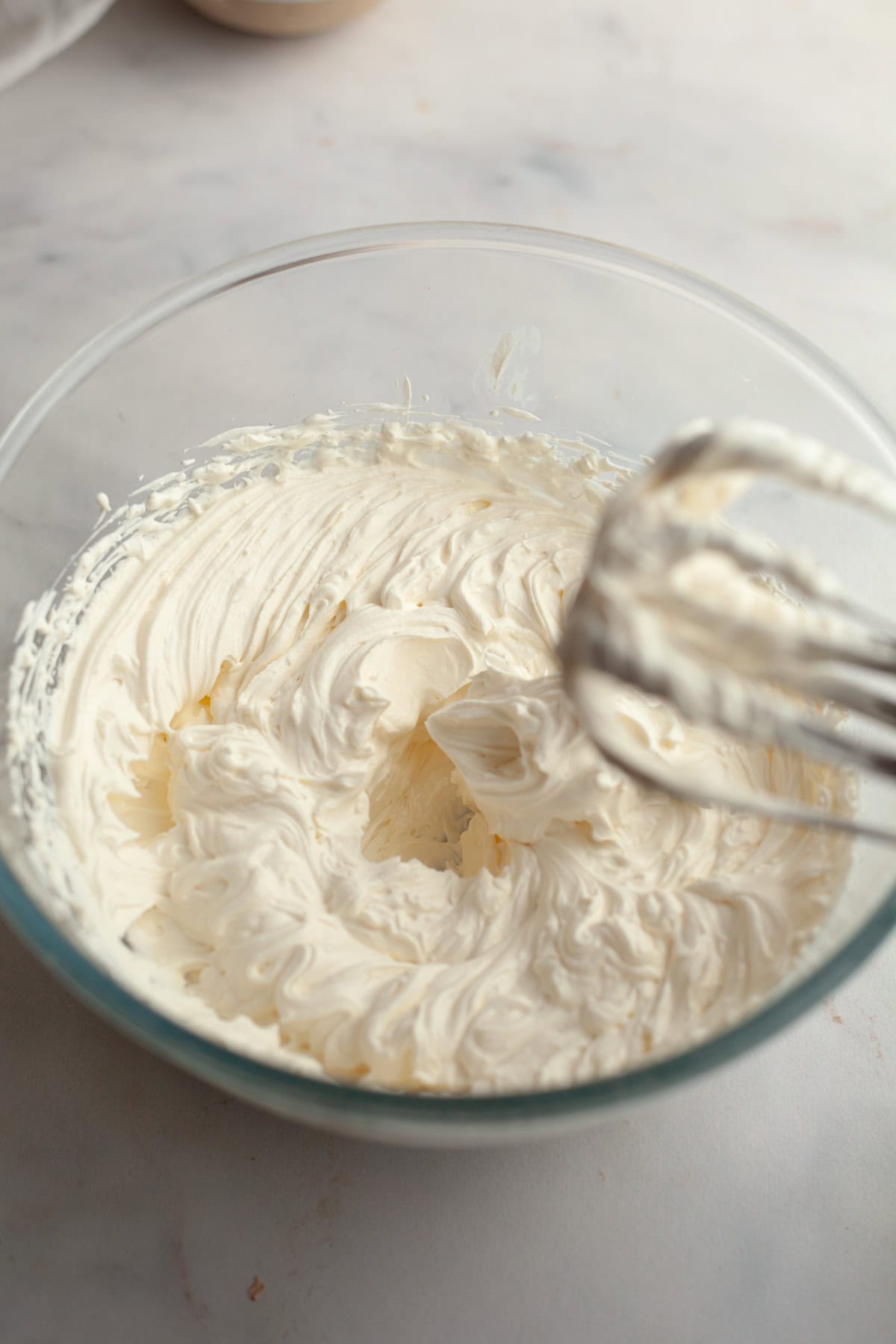 Cream cheese frosting in a large glass bowl.