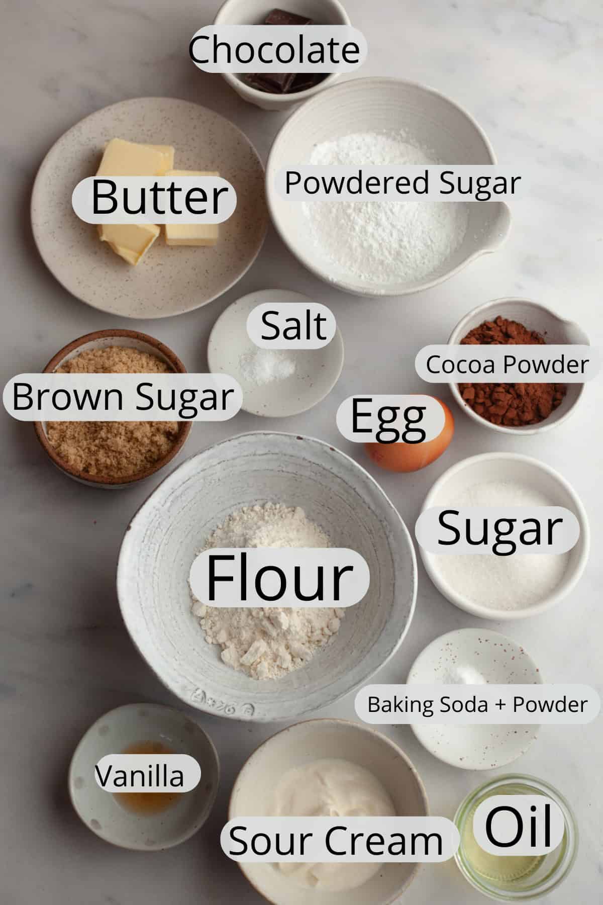 All the ingredients needed to make chocolate cupcakes with chocolate sour cream frosting, weighed out into small bowls.