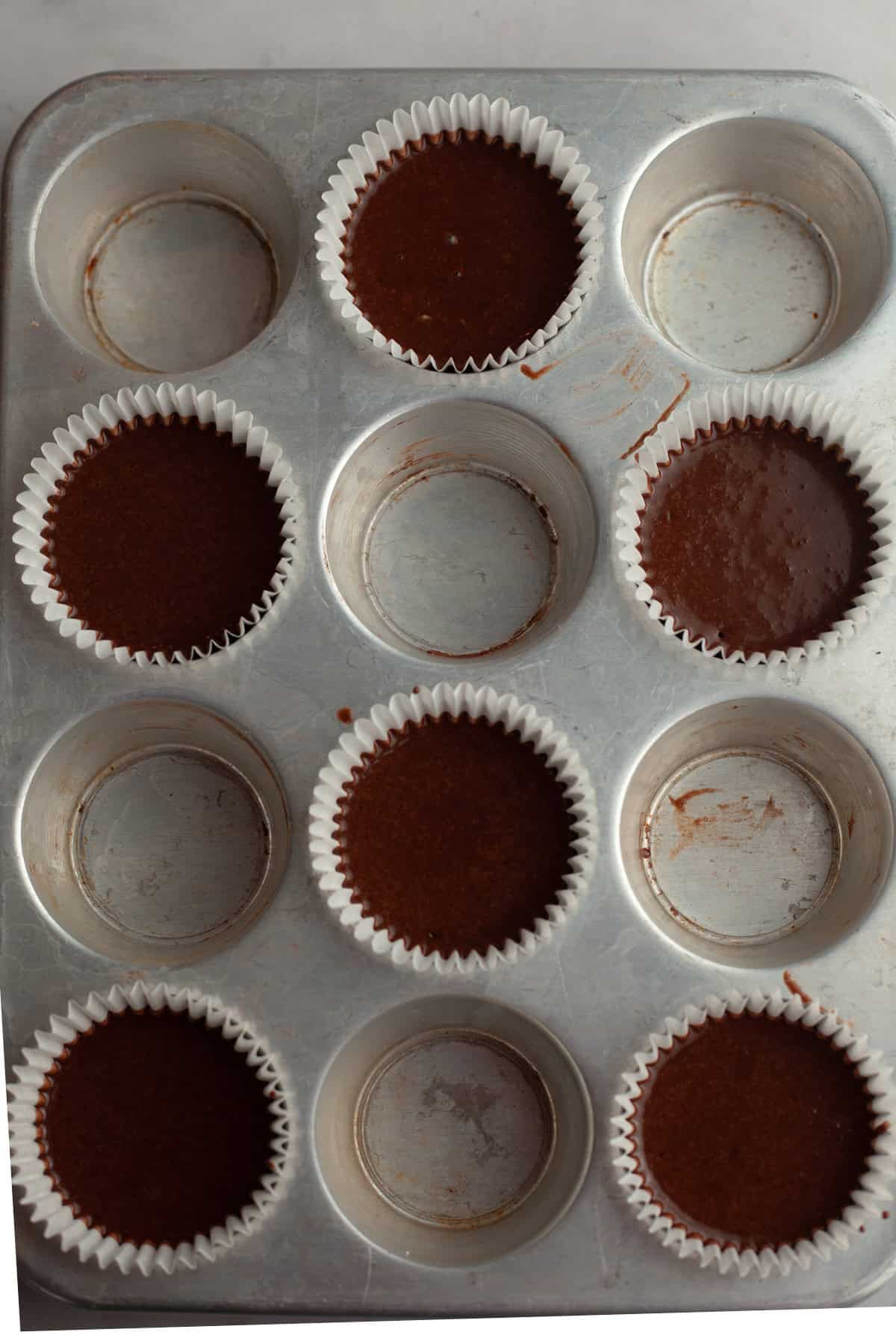 6 unbaked chocolate cupcakes in a cupcake pan.