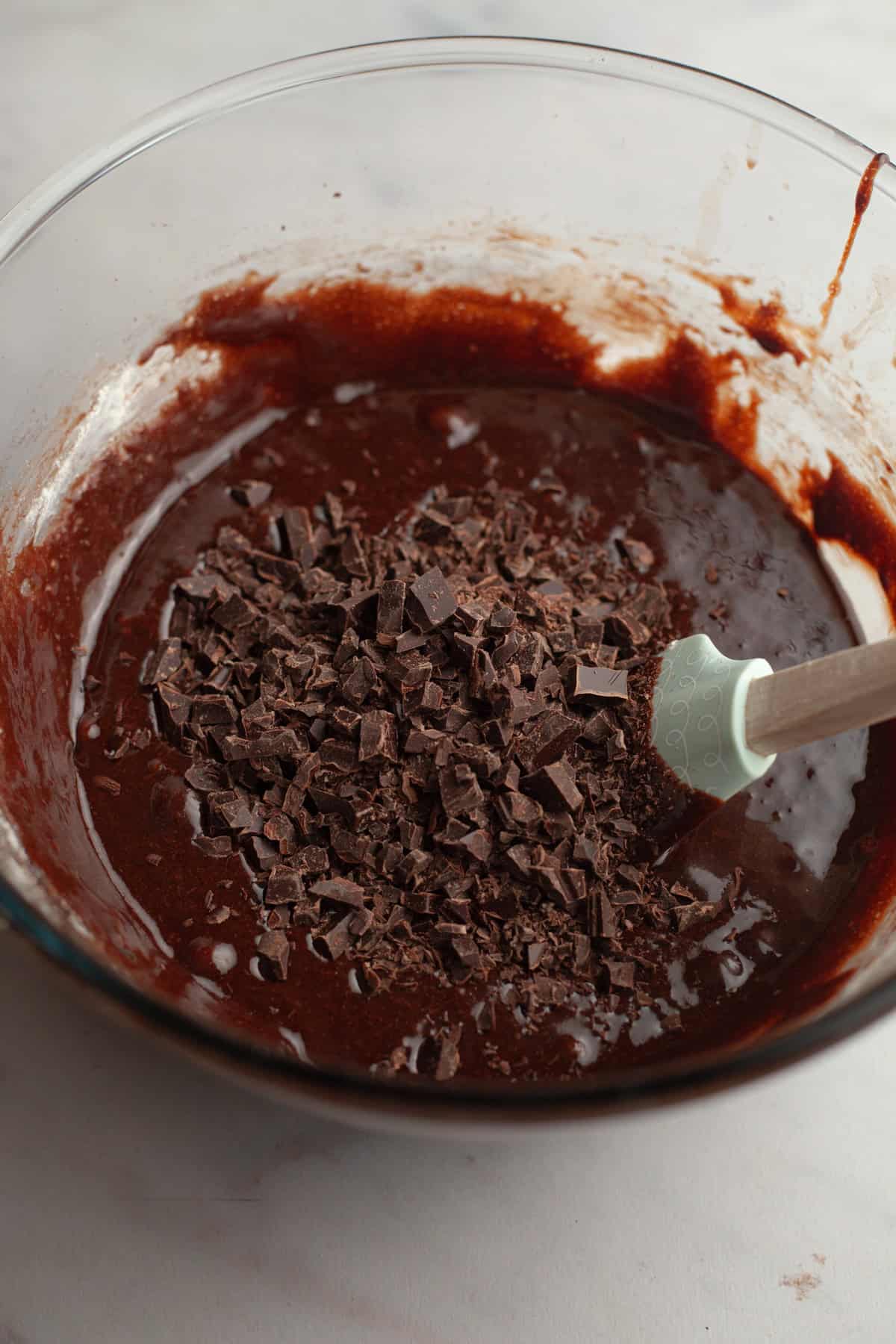 Brownie batter in a glass bowl with chopped chocolate.