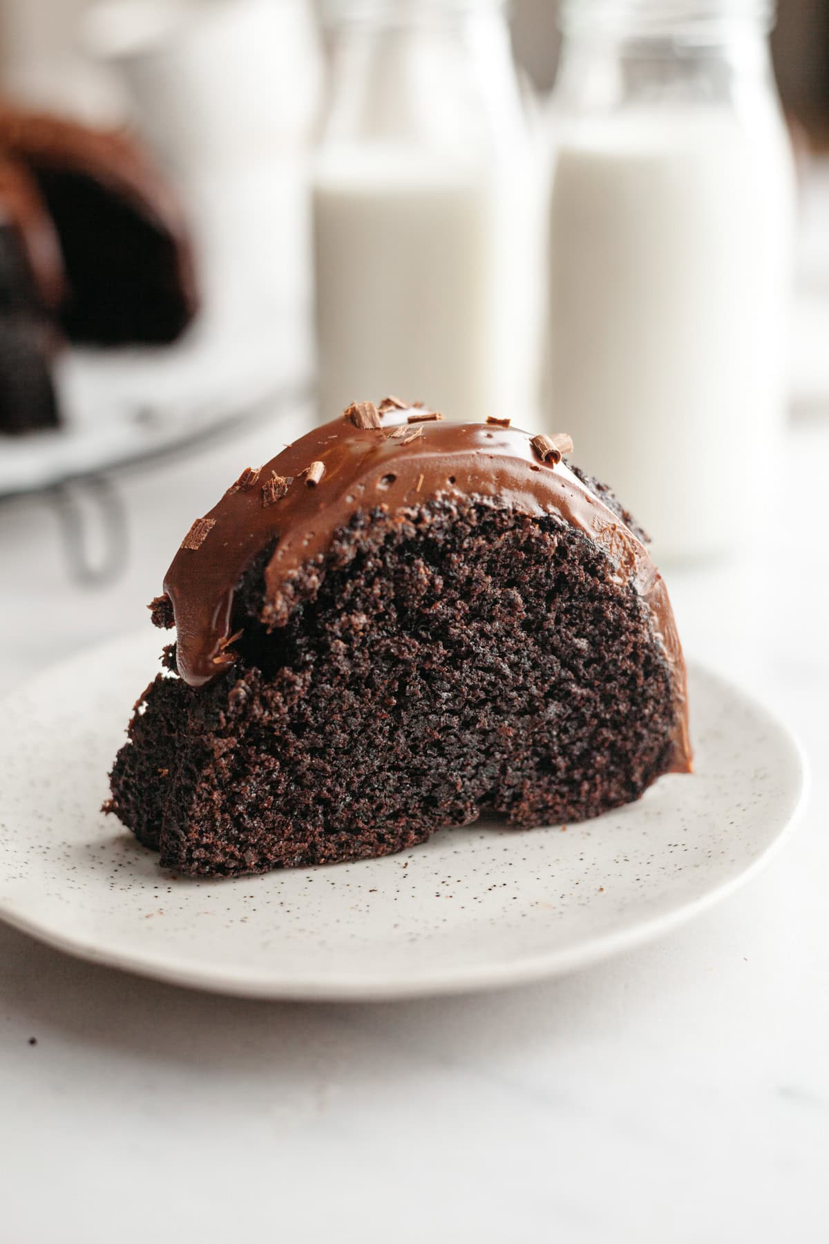 A slice of double chocolate bundt cake with ganache on a small plate.