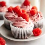 Close ups of chocolate cupcakes with raspberry buttercream, decorated with fresh raspberries.