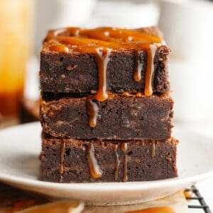 A stack of three brownies with salted caramel dripping down.