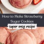 A close up of pink strawberry sugar cookies on parchment paper and a small plate, there are a few sliced strawberries.
