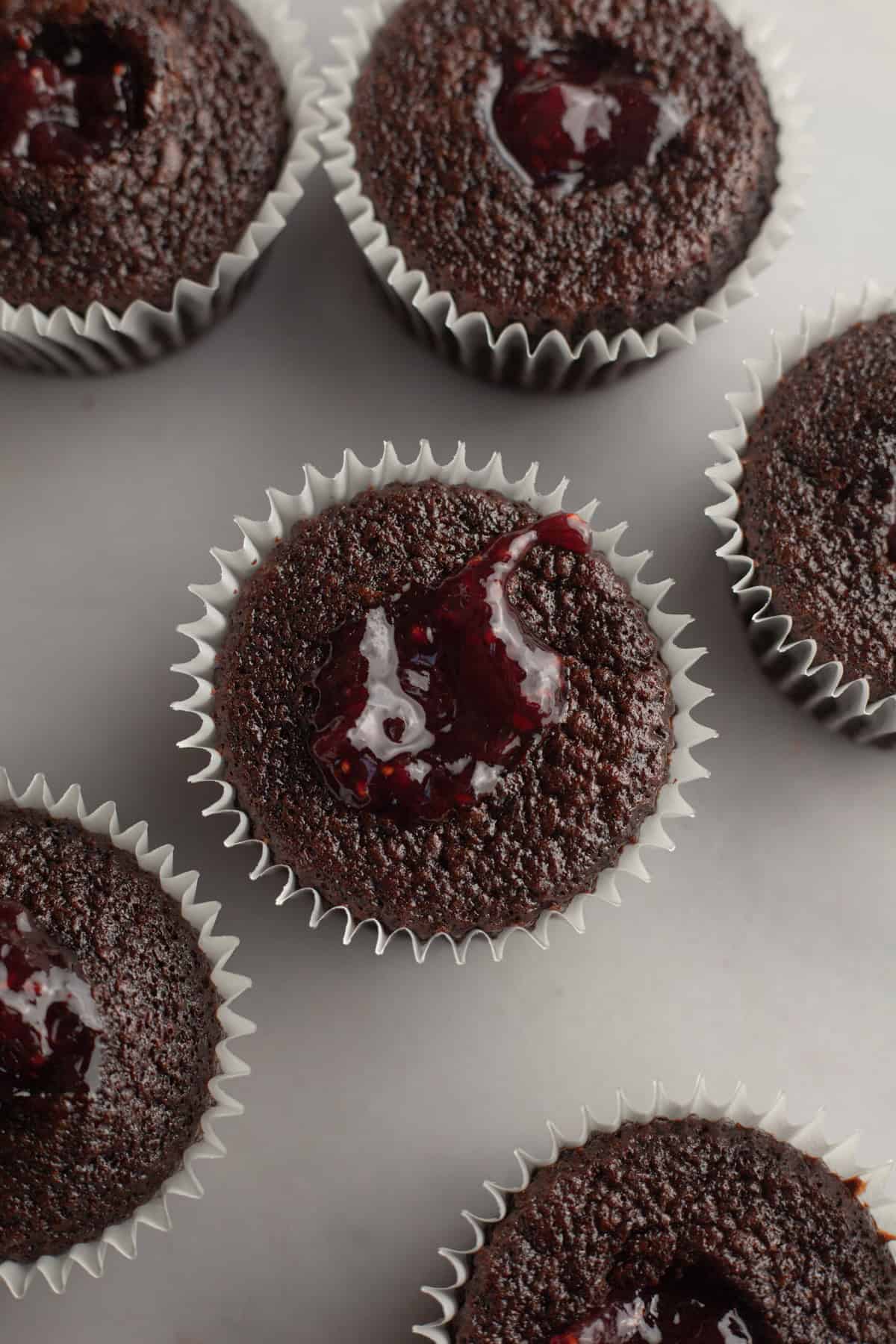 Chocolate cupcakes that have been cored and filled with raspberry jam.
