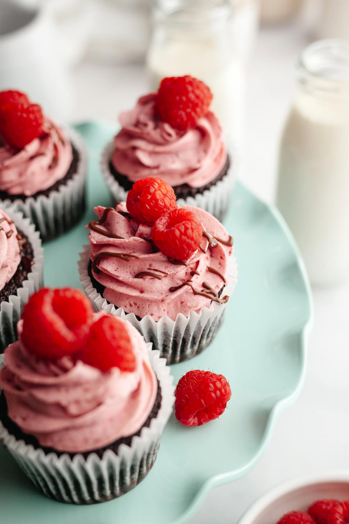 Close ups of chocolate cupcakes with raspberry buttercream, decorated with fresh raspberries.