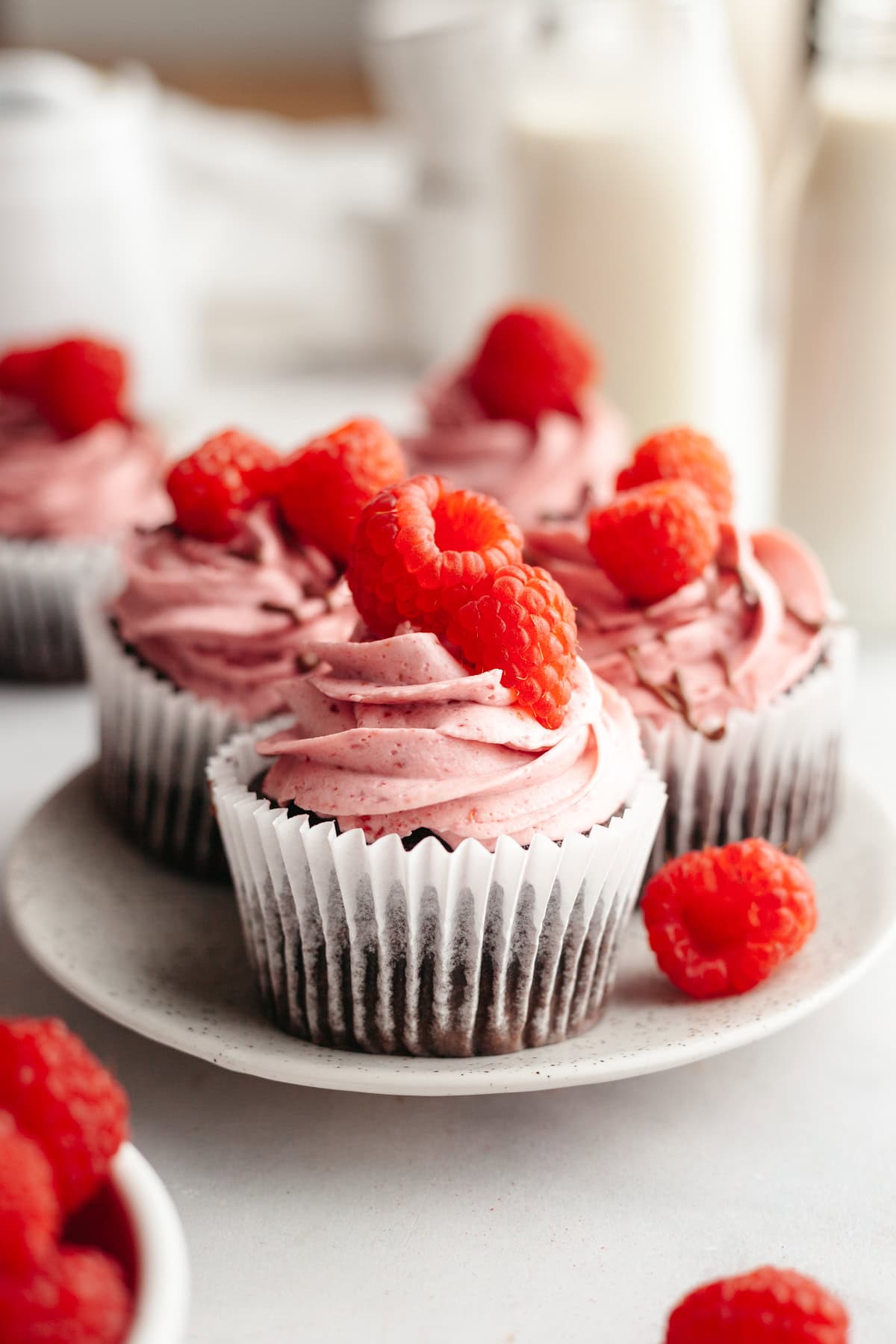 Close ups of chocolate cupcakes with raspberry buttercream, decorated with fresh raspberries.