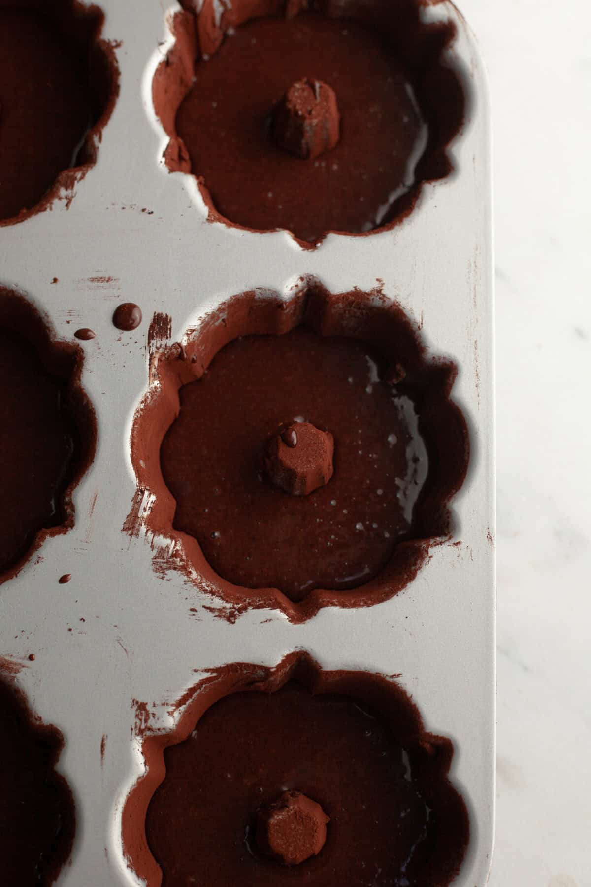 A mini bundt pan with unbaked chocolate cake batter.