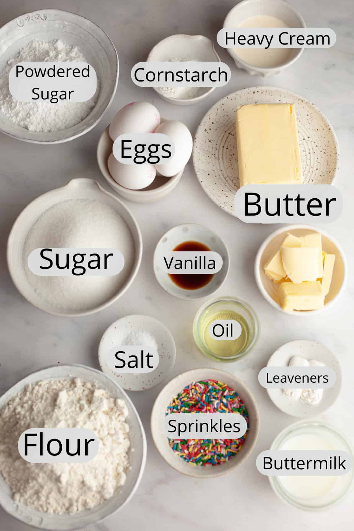 All the ingredients needed to make confetti sheet cake with vanilla frosting, weighed out into small bowls.