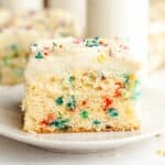 A slice of confetti sheet cake with vanilla frosting on a small plate.