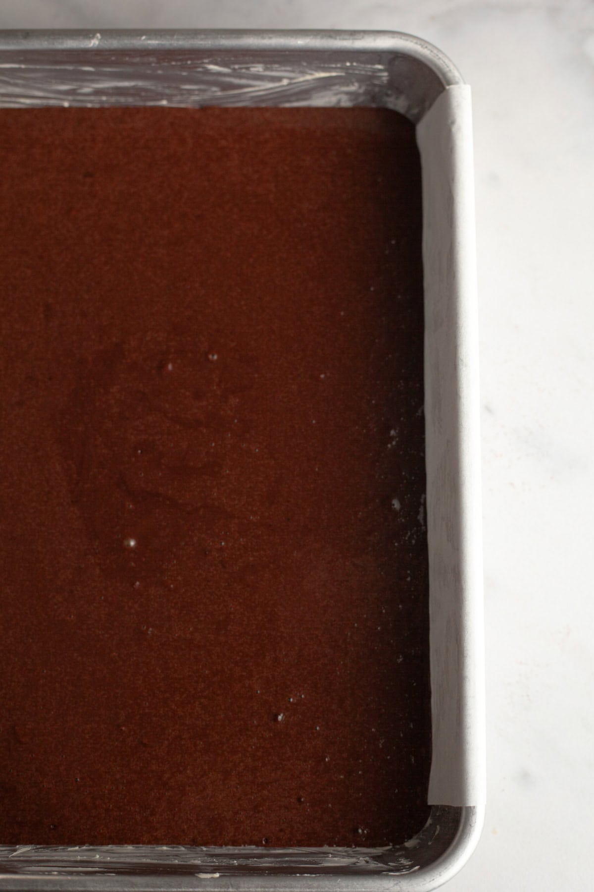 A rectangular sheet pan with unbaked chocolate cake.