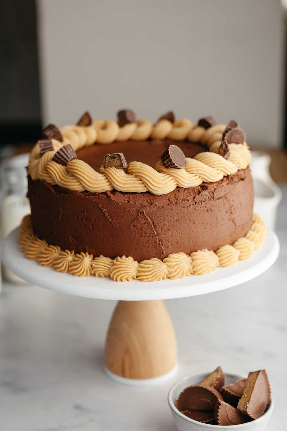 A peanut butter chocolate cake on a white cake stand.