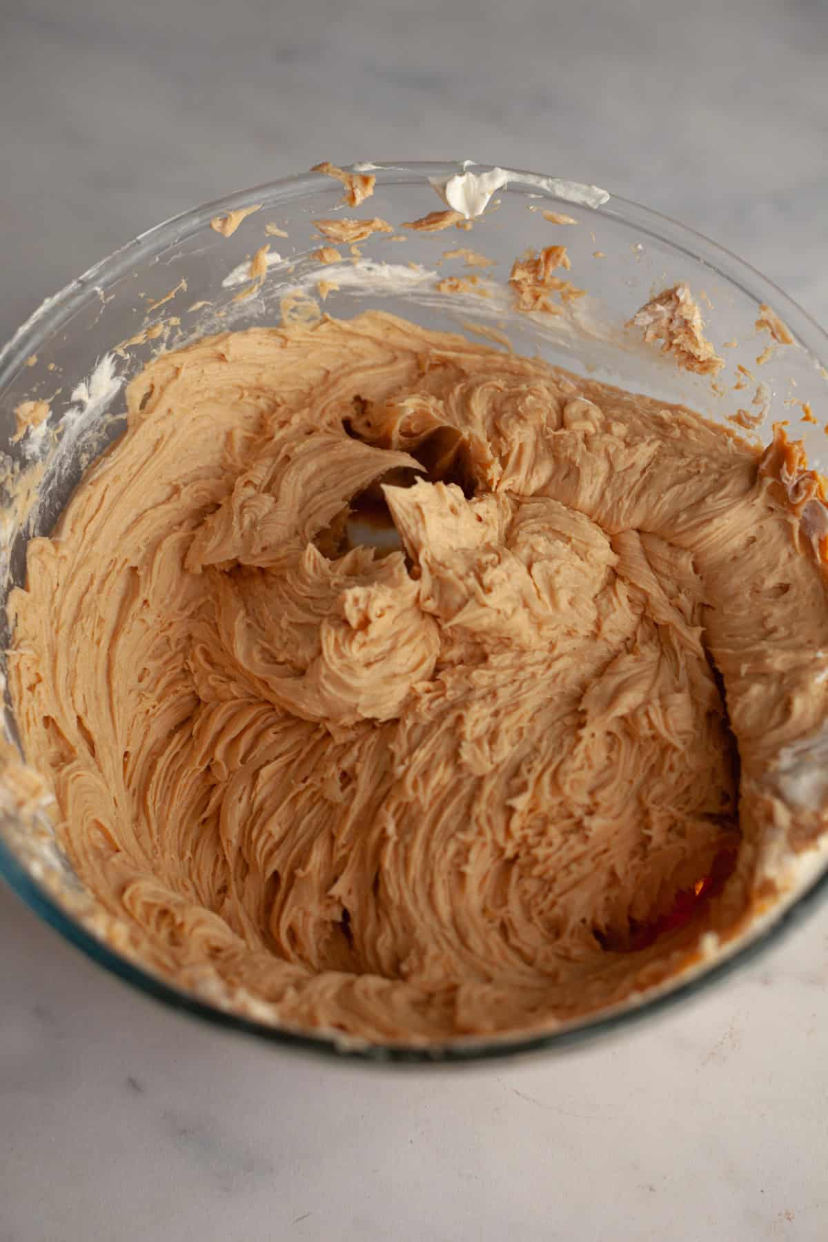 A large glass bowl with peanut butter frosting in it.