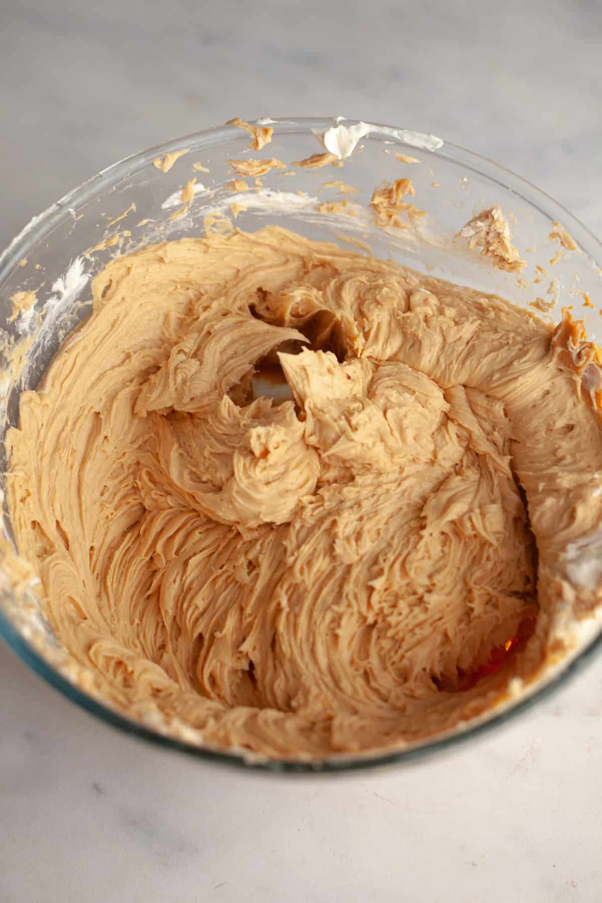 Peanut butter frosting in a glass bowl.