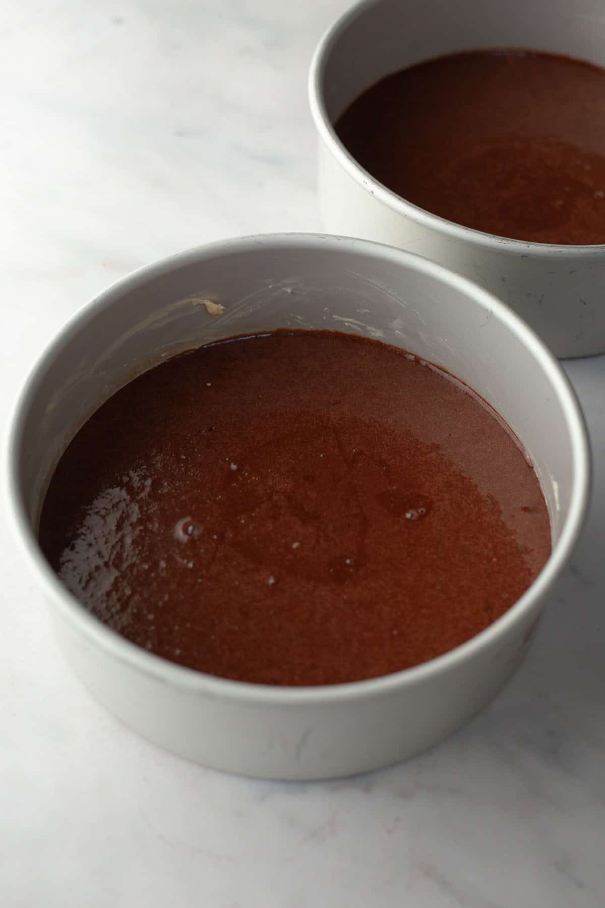 Unbaked chocolate cake in round cake pans.