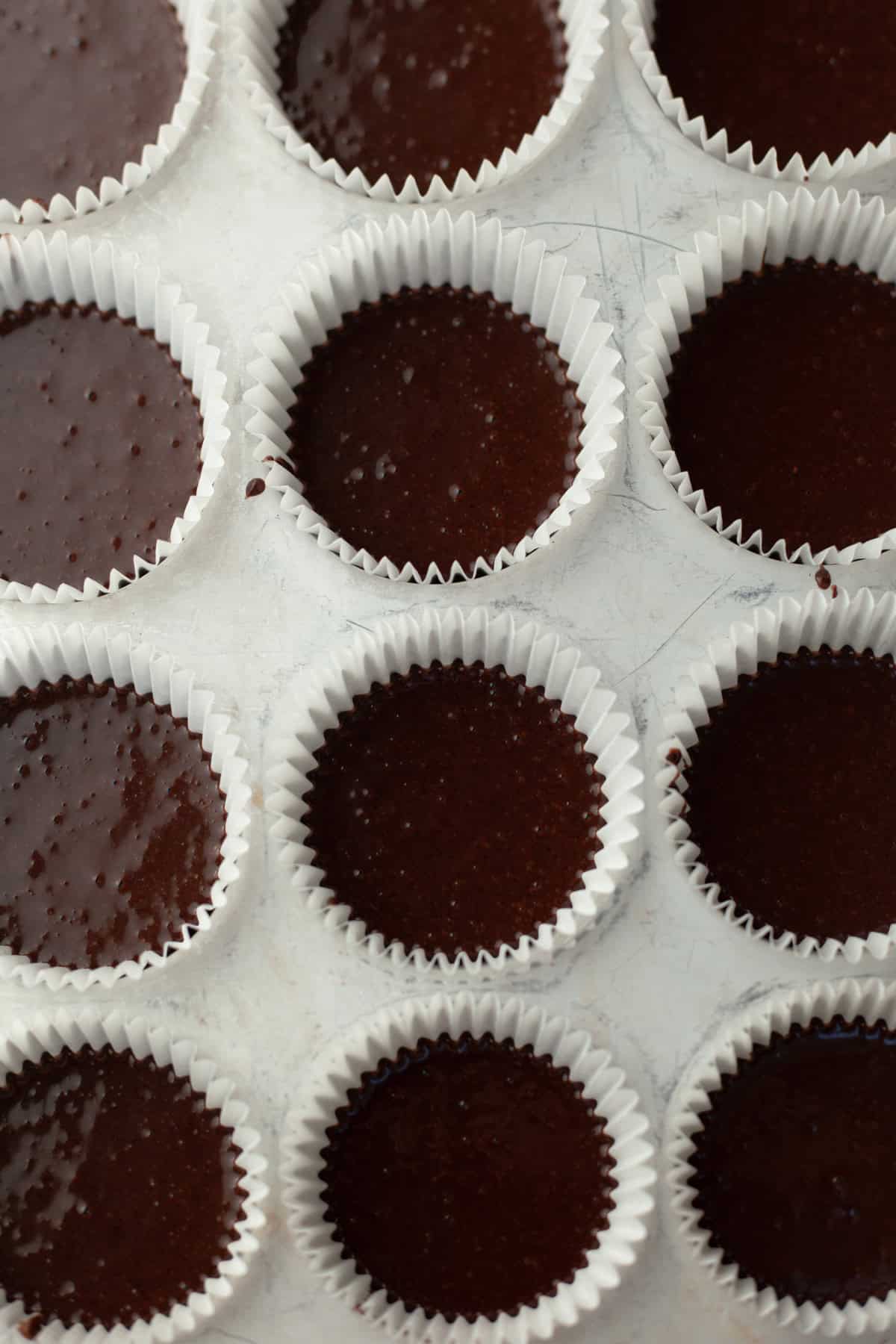 Unbaked chocolate cupcakes in a cupcake tin.