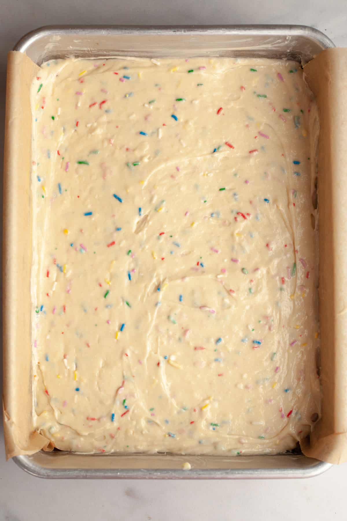 A sheet pan with unbaked funfetti cake batter.