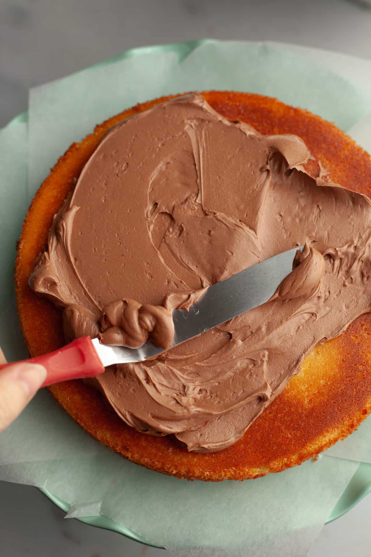 Chocolate frosting being spread on a cake.