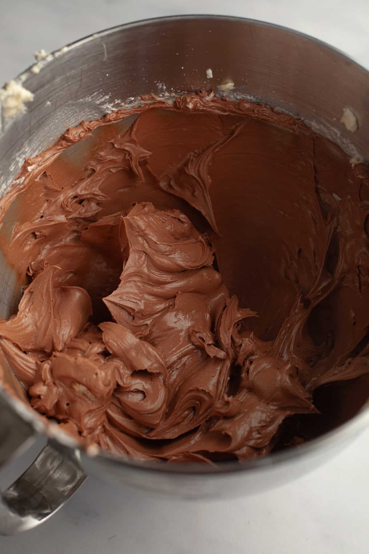 Chocolate frosting in a metal bowl.
