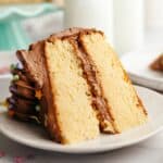 A slice of vanilla cake with chocolate frosting on a small plate.
