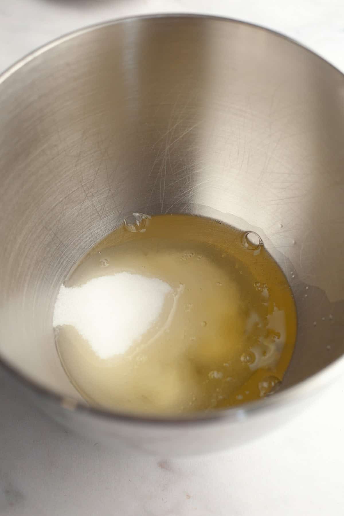A metal bowl with egg whites and sugar.