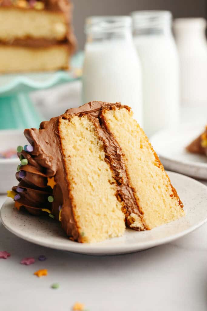 A slice of vanilla cake with chocolate frosting on a small plate.
