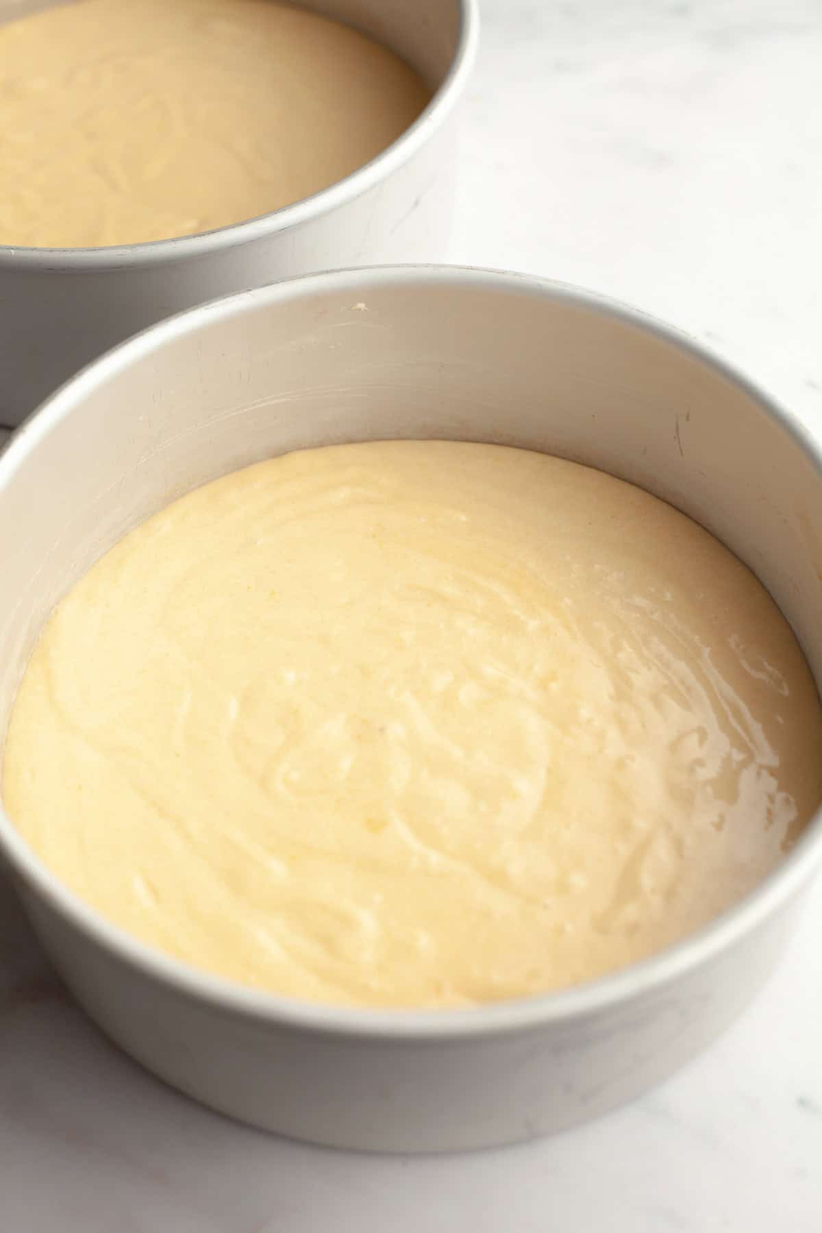 Vanilla cake batter in cake pans.