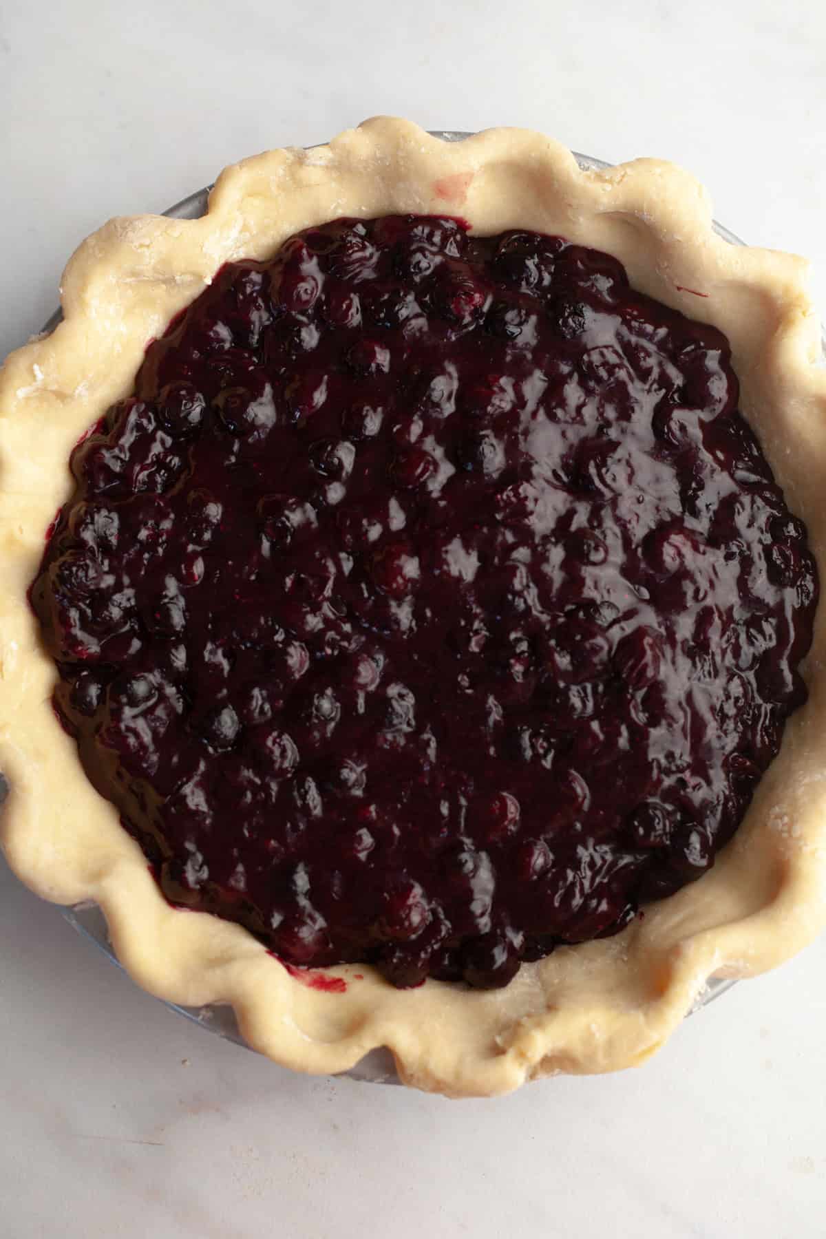 Unbaked pie filled with blueberry filling.