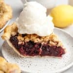 A slice of blueberry crumb pie with a large scoop of vanilla ice cream.