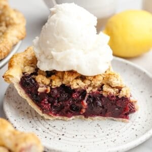 A slice of blueberry crumb pie with a large scoop of vanilla ice cream.